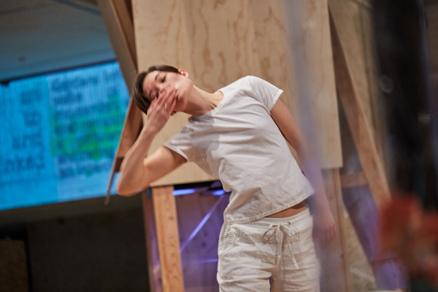 A woman dancing in a white t-shirt and white pants.