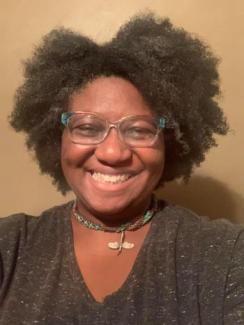 Picture of A Beautiful Black woman who is smiling and has  full afro.