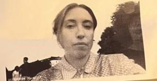 a selfie of a white woman with a collared shirt in a field