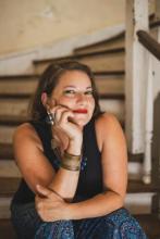 brunette white woman sitting on steps with hand under chin 