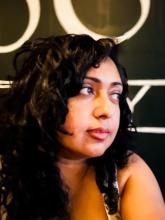 Brown woman with curly hair looking towards the left