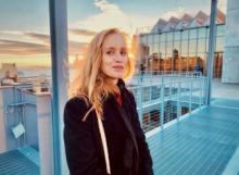 Middle aged woman standing outside at the Whitney museum with wind in hair. 