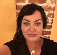 brown haired woman against yellow and brick wall