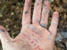 white hand covered in wax and ash w red ink pen symbol drawings