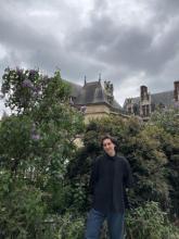 The author in a black collared shirt against a blooming lilac bush and stormy sky.