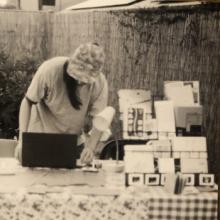 picture of a picture of ryan greene at a table with zines in the garden at palabras bilingual bookstore looking down at a laptop