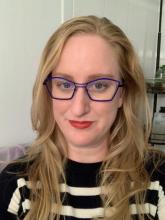 blond haired woman wearing blue glasses with black and white striped sweater