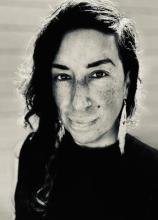 black and white portrait of heidi andrea restrepo rhodes with long dark hair, dangly earrings, and a black top.